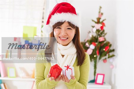Beautiful Asian woman showing her Christmas gift, indoor/inside her house