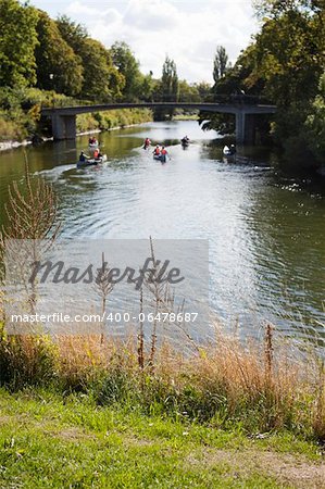 Group of canoes in a pieceful scene in the green environment surrounding Malmoe canal. Focus is shallow.