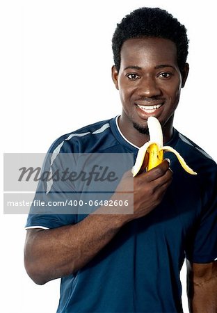 Young fit guy eating banana. Posing in front of camera