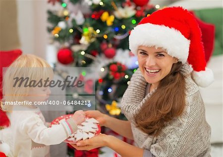 Happy mother giving baby Christmas cookies