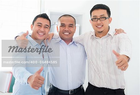 Thumbs up Southeast Asian businessmen standing in office