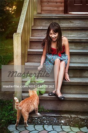 Girl in red dress playing with cat