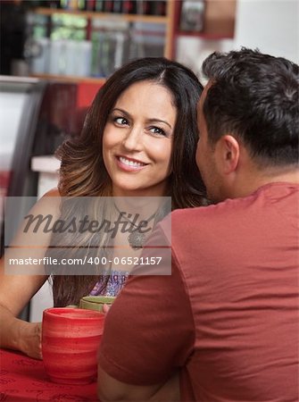 Skeptical Hispanic woman listening to man talk in cafe