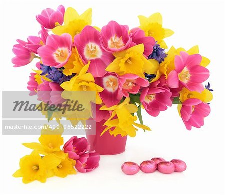 Tulip, daffodil and hyacinth flower arrangement in a pink vase with a chocolate easter egg group over white background.