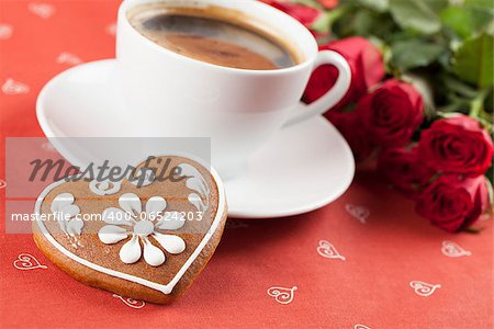 Gingerbread heart with coffee and red roses on red background. Shallow dof