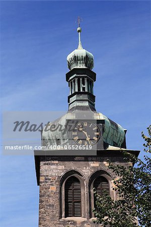 Closeup of old belfry with clock against blue sky