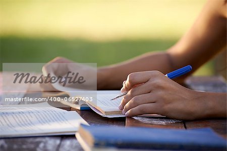 Young women and education, close up of hands of girl studying for college exam in park. Side view, copy space