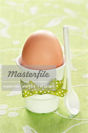 Egg in egg cup for breakfast on green napkin.
