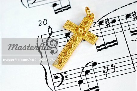 A golden cross on the top of a music sheet concept of religion