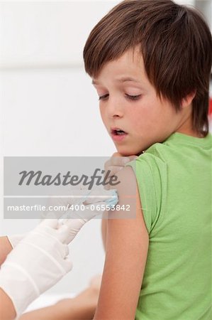 Worried boy getting an injection looking at the needle - focus on the arm