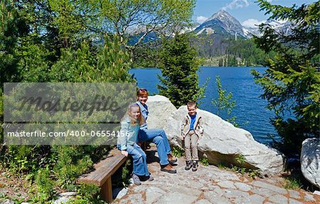 Strbske Pleso spring view with mountain lake and family on bench  (Slovakia)