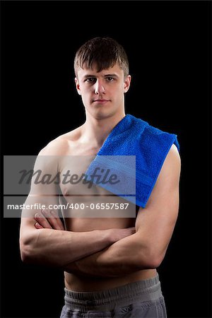 Young muscular man page with a blue towel on a black background