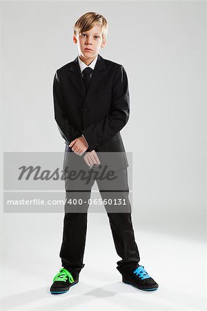 Studio portrait of serious looking young boy wearing black suit and colorful shoes