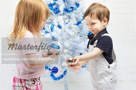 two beautiful happy children decorate christmas tree