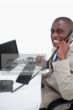 Side view of a businessman answering the phone while using a monitor against a white background