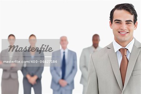 Smiling salesman with colleagues behind him against a white background