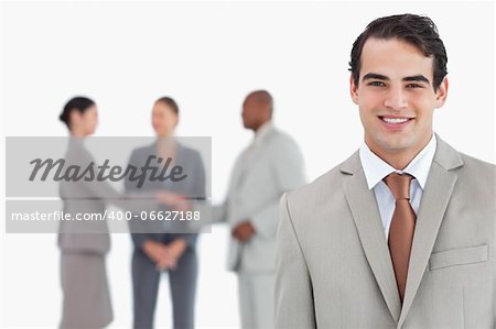 Smiling salesman with businesspeople behind him against a white background