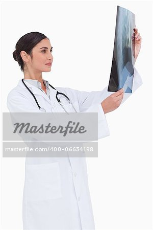 Side view of female doctor looking at x-ray against a white background