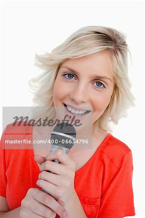 Smiling teenager singing in a cordless microphone against a white background
