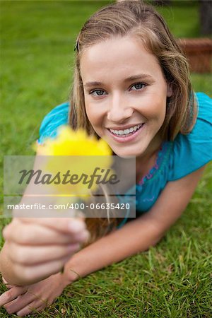 Smiling student holding a beautiful yellow flower while looking straight at the camera