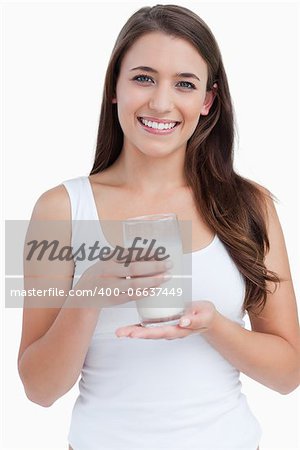 Smiling woman holding a glass of milk against a white background