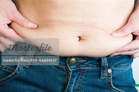 Woman pinching fat from her abdomen. Close up shot