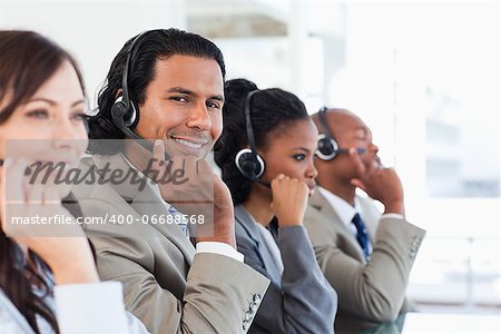 Young smiling call centre employee working among his team