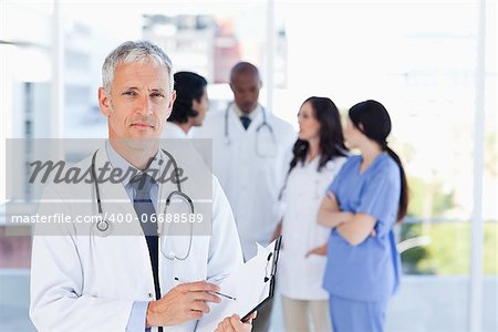 Mature doctor pointing seriously at something on his clipboard