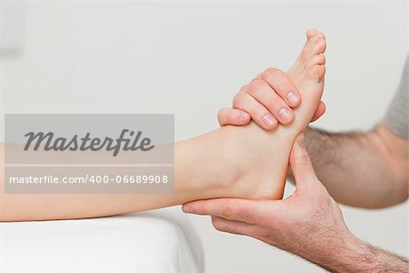 Hands of an osteopath massaging a foot in a room