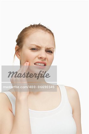 Young woman massaging her jaw against white background