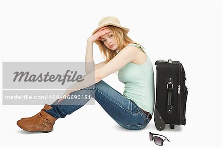 bored woman sitting near a suitcase against white background