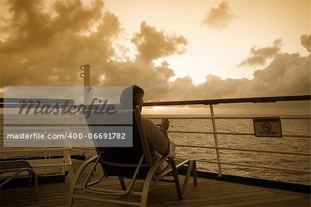 A man sitting on the deck of a ship looking out to sea