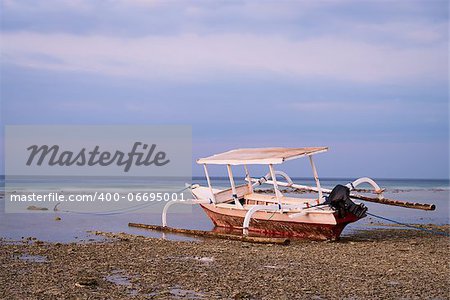 Boat with wings on beach in sunset time at low tide, Indonesia