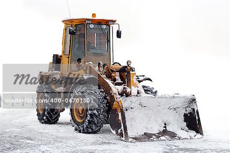 old tractor with a bucket on snowy winter playground with clipping path