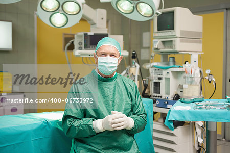 Surgeon smiling while joining his hands together in a surgical room