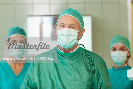 Surgeon with two interns behind him in a surgical room