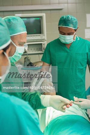 Medical team taking a scalpel from the hand of a colleague in a surgical room