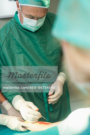 Surgeon using a scalpel to cut the skin of a patient in a surgical room