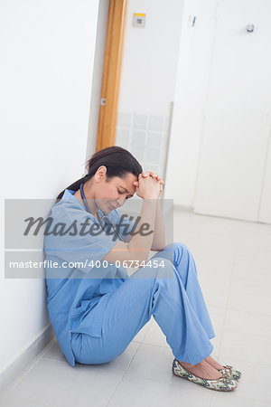 Sad nurse sitting on the floor in hospital ward