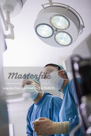 Doctors next to surgical light in operating theater