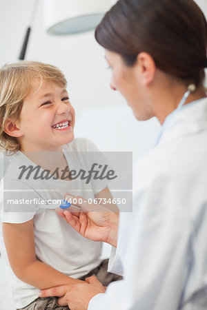 Doctor taking temperature of a child in examination room
