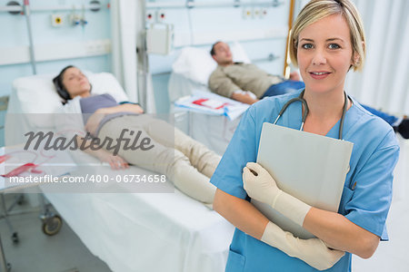 Nurse standing next to transfused patients in hospital ward