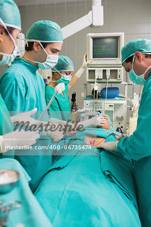 Side view of a surgical team next to a patient in an operating theatre