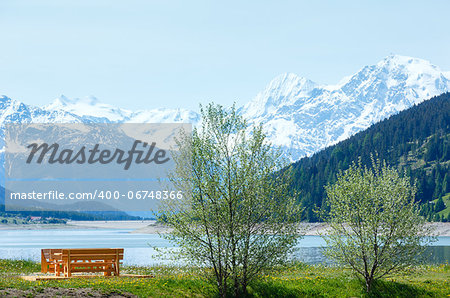 Reschensee ( or Lake Reschen) summer landscape with  blossoming meadow picnic wooden bench near (Italy)