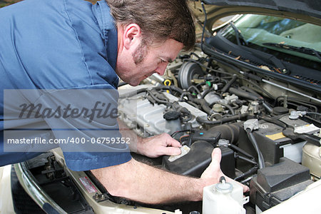 Auto mechanic under the hood, working on a car engine.