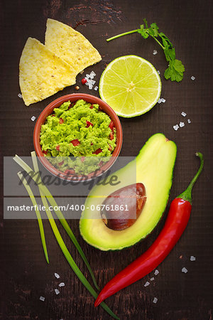 Ingredients for guacamole and guacamole dip on a dark background.