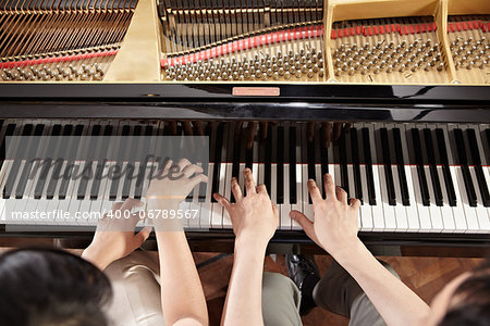 Two people, a couple playing piano duet, showing mostly their hands