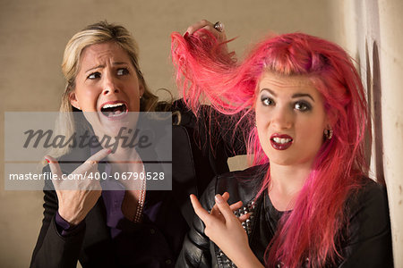 Shocked blond woman holding pink hairdo of teenager