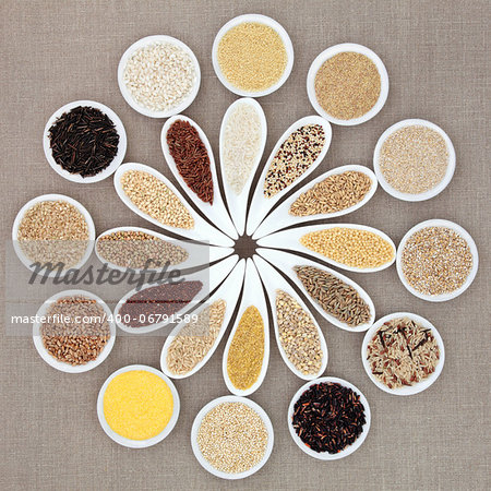 Large grain and cereal food selection in white porcelain bowls over hessian background.