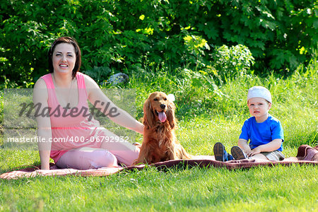 Yong mother with toddler and dog sitting on rad on nature